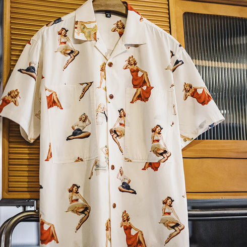 White shirt with vintage-style pin-up girl print on a hanger against a window background.